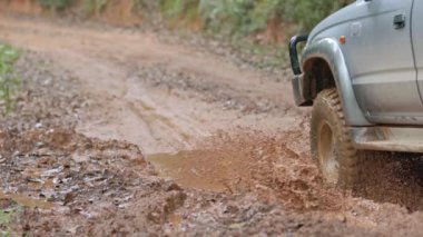 Arabalar off-road yollarında koşuyor ve doğal yollara çamur sıçrıyor. Çamurlu yolda off-road yolculuğu. Offroad seyahat ve sürüş konsepti, çamurlu bir yol ile kırsal bir araziye yakın tekerlek.
