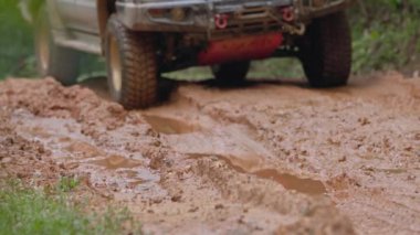 Arabalar off-road yollarında koşuyor ve doğal yollara çamur sıçrıyor. Çamurlu yolda off-road yolculuğu. Offroad seyahat ve sürüş konsepti, çamurlu bir yol ile kırsal bir araziye yakın tekerlek.