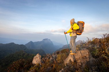 Bir adam sırt çantasıyla dağlarda yürüyüş yapıyor. Sabahları dağlarda yürüyüş yaparken gün ışığı yumuşakken.