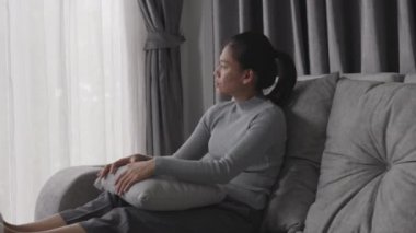 Depresyonda olan bir kadın kanepede oturur ve pencereden dışarı bakar. İlişkide Depresyon Sorununun Atmosferi, Ailede Ölüm. Stres ve aile sorunları kavramı.