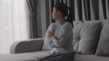 Depresyonda olan bir kadın kanepede oturur ve pencereden dışarı bakar. İlişkide Depresyon Sorununun Atmosferi, Ailede Ölüm. Stres ve aile sorunları kavramı.