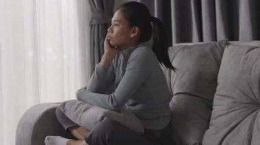 Depresyonda olan bir kadın kanepede oturur ve pencereden dışarı bakar. İlişkide Depresyon Sorununun Atmosferi, Ailede Ölüm. Stres ve aile sorunları kavramı.