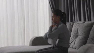Depresyonda olan bir kadın kanepede oturur ve pencereden dışarı bakar. İlişkide Depresyon Sorununun Atmosferi, Ailede Ölüm. Stres ve aile sorunları kavramı.