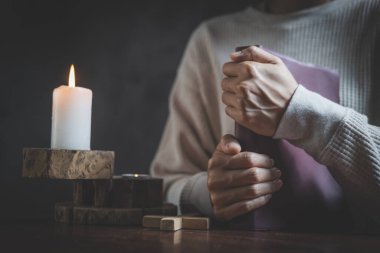 Eller kadın İncil ve çapraz, dua sabah kadın ile dua tutarak dua birlikte gündoğumu arka plan üzerinde.