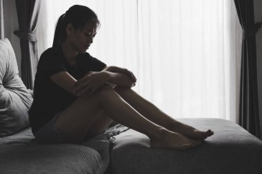 Depresyonda olan bir kadın kanepede oturur ve pencereden dışarı bakar. İlişkide Depresyon Sorununun Atmosferi, Ailede Ölüm. Stres ve aile sorunları kavramı.