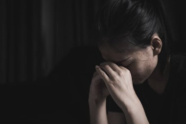 Karanlık bir odada oturan üzgün bir kadın, depresyon, kampanya kadınlara karşı şiddeti durdurdu. cinsel istismar, insan kaçakçılığı, aile içi şiddet uluslararası kadınlara tecavüz,