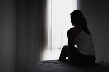Karanlık odada oturan genç kadınların silueti hayat sorunuyla acı çekiyor. Şiddete son verin, kadınlara yönelik şiddete son verin, aile içi şiddet, insan kaçakçılığı.