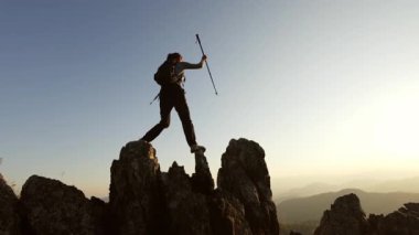 Sunset 'te bir dağın tepesinde duran bir kadının silueti, kadın tırmanışçı zirveye ulaşıyor, manzaranın tadını çıkarıyor..