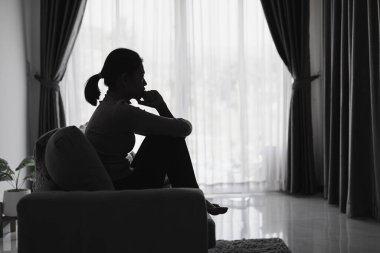 Evdeki kanepede oturan üzgün ve bunalımlı kadın. Kadınlara yönelik şiddeti durdurun, aile içi şiddet mağduru. Depresyon nedeniyle intihar.
