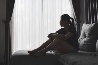 Evdeki kanepede oturan üzgün ve bunalımlı kadın. Kadınlara yönelik şiddeti durdurun, aile içi şiddet mağduru. Depresyon nedeniyle intihar.
