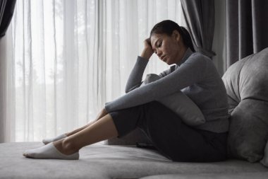 Evdeki kanepede oturan üzgün ve bunalımlı kadın. Kadınlara yönelik şiddeti durdurun, aile içi şiddet mağduru. Depresyon nedeniyle intihar.