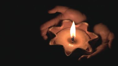 Ellere güven. Karanlığın içinde yanan bir mumu tutan eller. Tanrıya dua et, gece arkaplanı..