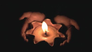 Ellere güven. Karanlığın içinde yanan bir mumu tutan eller. Tanrıya dua et, gece arkaplanı..