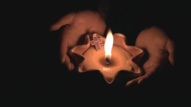 Ellere güven. Karanlığın içinde yanan bir mumu tutan eller. Tanrıya dua et, gece arkaplanı..