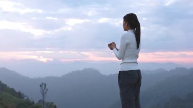 Hıristiyan bir kadın sabah bir dağın zirvesinde dua ediyor. Tanrı 'nın lütfu için dua et. Barış ve umut kavramı.
