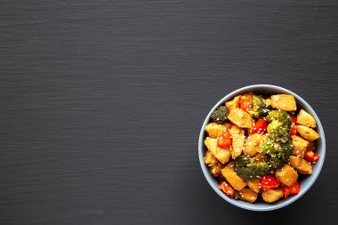 Ev yapımı Tavuk ve Brokoli Kızartması siyah arka planda bir kasede, en iyi görünümde. Dümdüz, tepeden, yukarıdan. Metin için boşluk.