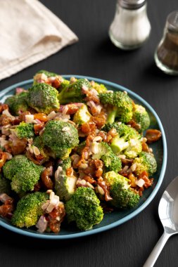 Ev yapımı Brokoli Bacon Salatası. Siyah arka planda bir tabakta..