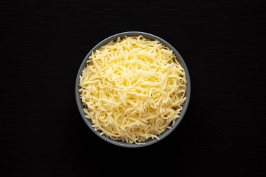 Siyah bir yüzey üzerinde öğütülmüş Mozzarella Peyniri. Dümdüz, tepeden, yukarıdan. 