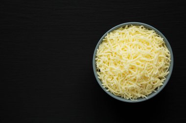 Siyah bir yüzey üzerinde öğütülmüş Mozzarella Peyniri. Dümdüz, tepeden, yukarıdan. Metin için boşluk.