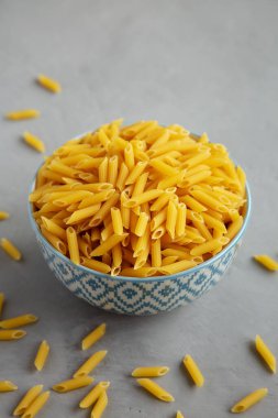 Ev yapımı Çiğ Mini Penne Makarnası Gri arka planda, kenar manzaralı bir kasede. 