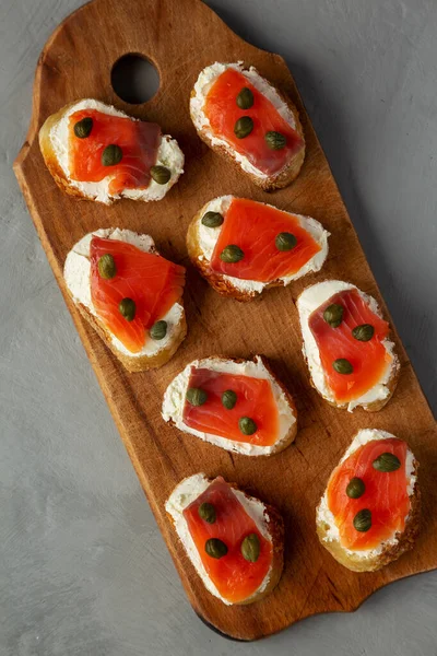 stock image Homemade Lox And Cream Cheese Crostini on a wooden board, top view. Flat lay, overhead, from above. 