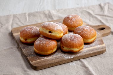 Homemade Apricot Polish Paczki Donut with Powdered Sugar on a Wooden Board, side view. clipart
