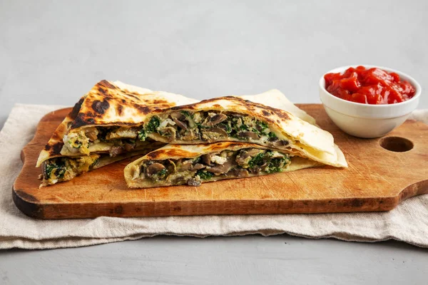 stock image Homemade Spinach and Mushroom Quesadilla with Salsa on a rustic wooden board, low angle view.