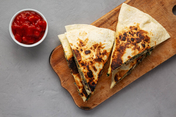 Homemade Spinach and Mushroom Quesadilla with Salsa on a rustic wooden board, top view. Flat lay, overhead, from above. 
