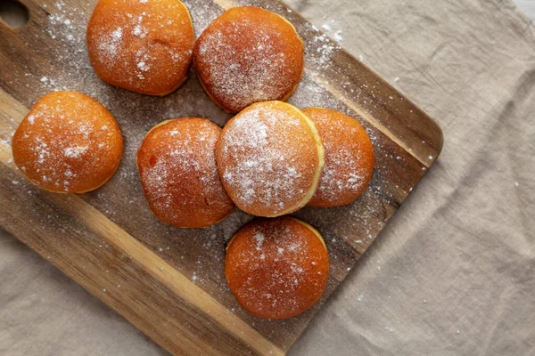 Tahta bir tahtanın üzerinde toz şekerli ev yapımı kayısı, Polonyalı Paczki Donutu. Dümdüz, tepeden, yukarıdan. Metin için boşluk.