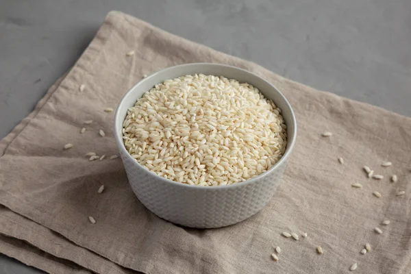 stock image Raw Organic Carnaroli Rice in a Bowl on a gray background, side view.