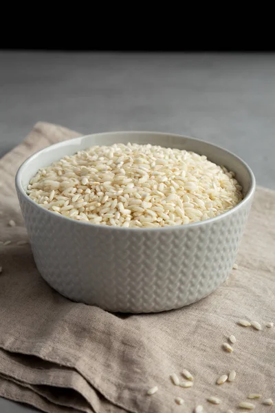 stock image Raw Organic Carnaroli Rice in a Bowl on a gray surface, side view. 