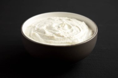 Ev yapımı Ranch Sressing Siyah arka planda, yan manzaralı bir kasede.