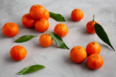 Gri arka planda çiğ organik Mandarinler, kenar görünüm.