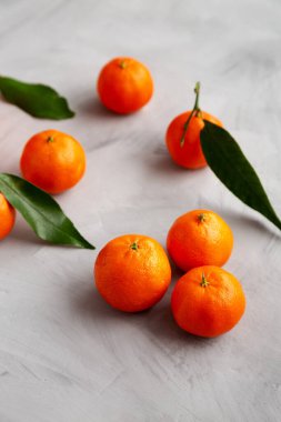 Gri arka planda çiğ organik Mandarinler, düşük açılı görünüm.