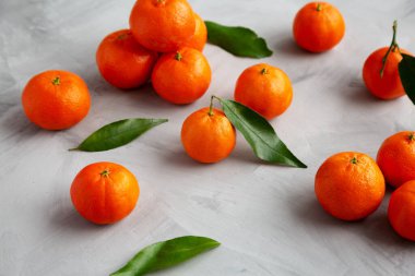 Gri arka planda çiğ organik Mandarinler, düşük açılı görünüm.