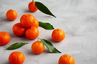 Gri arka planda çiğ organik Mandarinler, yan görüş. Boşluğu kopyala.