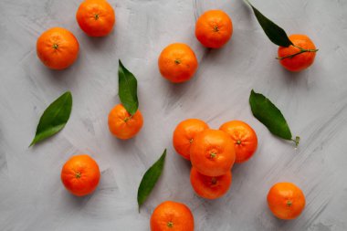 Gri arka planda çiğ organik Mandarinler, üst manzara. Dümdüz, tepeden, yukarıdan.