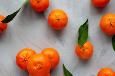 Gri arka planda çiğ organik Mandarinler, üst manzara. Dümdüz, tepeden, yukarıdan. 
