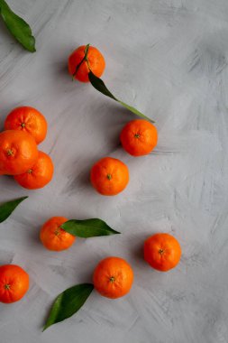 Gri arka planda çiğ organik Mandarinler, üst manzara. Dümdüz, tepeden, yukarıdan. Boşluğu kopyala.