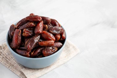 Bowl 'daki Pitted Organic Date' ler gri arka planda, düşük açılı görüntüde. Boşluğu kopyala.