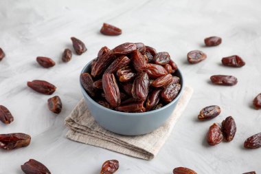 Bowl 'daki Pitted Organic Date' ler gri arka planda, düşük açılı görüntüde. Yakın plan..