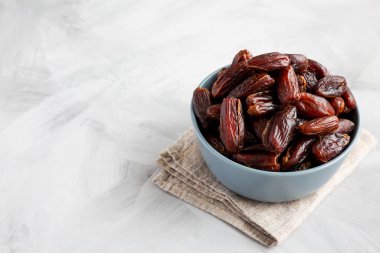 Bowl 'daki Pitted Organic Date' ler gri arka planda, düşük açılı görüntüde. Metin için boşluk.