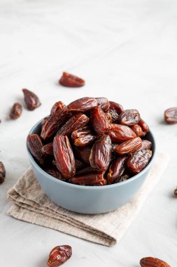 Bowl 'daki Pitted Organik Hurmalar, gri arka plan, yan görüş. Boşluğu kopyala.