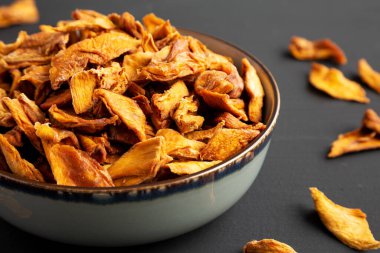 Lezzetli Organik Kurutulmuş Mango Meyvesi Siyah bir yüzey üzerinde bir kasede.