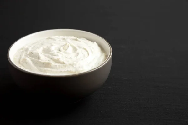 Homemade Ranch Dressing in a Bowl on a black background, side view. Space for text.