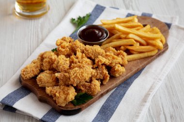 Homemade Popcorn Chicken with BBQ Sauce on a Rustic Wooden Board, side view.
