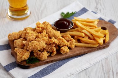 Homemade Popcorn Chicken with BBQ Sauce on a Rustic Wooden Board, low angle view.