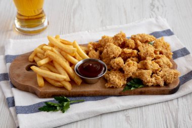 Homemade Popcorn Chicken with BBQ Sauce on a Rustic Wooden Board, low angle view.