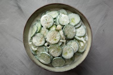 Homemade Cucumber Salad with Sour Cream and Onions in a Bowl, top view.