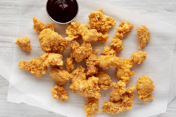 Homemade Popcorn Chicken with BBQ Sauce on a white wooden background, top view. Flat lay, overhead, from above.